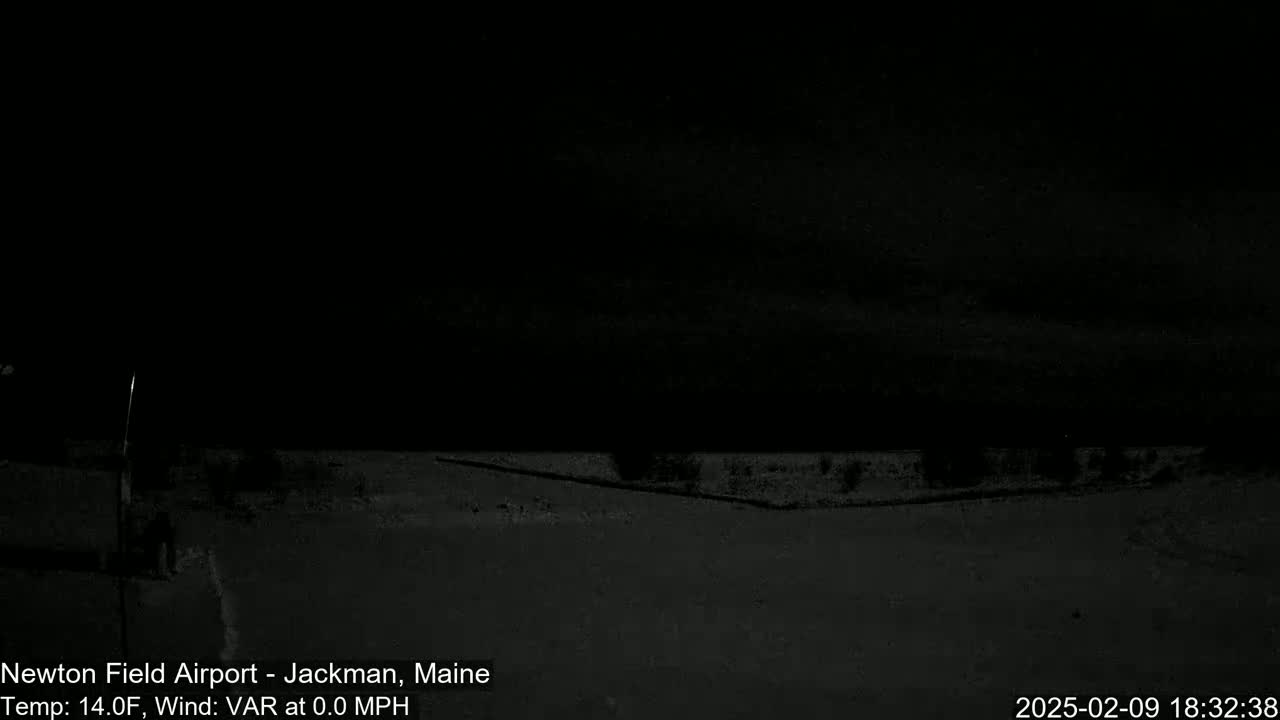 A dark, nighttime scene shows a flat, snow-covered ground under a nearly cloudless sky.