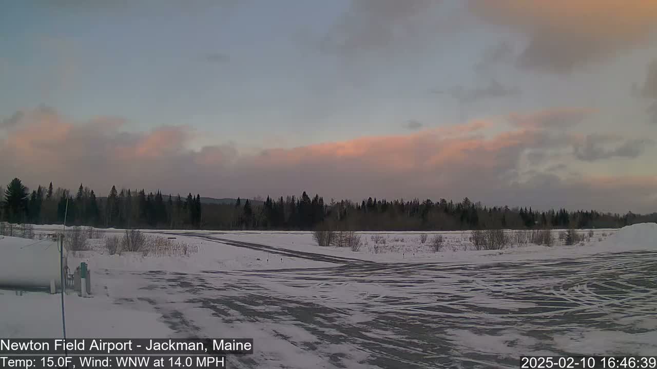 A snow-covered airfield is visible under a partly cloudy sky with a pinkish hue near the horizon.