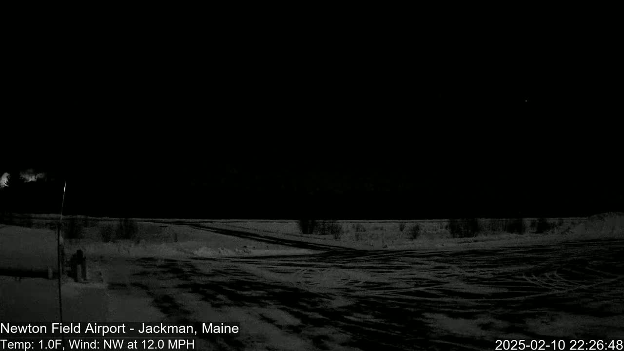 A snow-covered, dark airfield is visible under a clear night sky with a northwest wind at 12 mph and a temperature of 1 degree Fahrenheit.