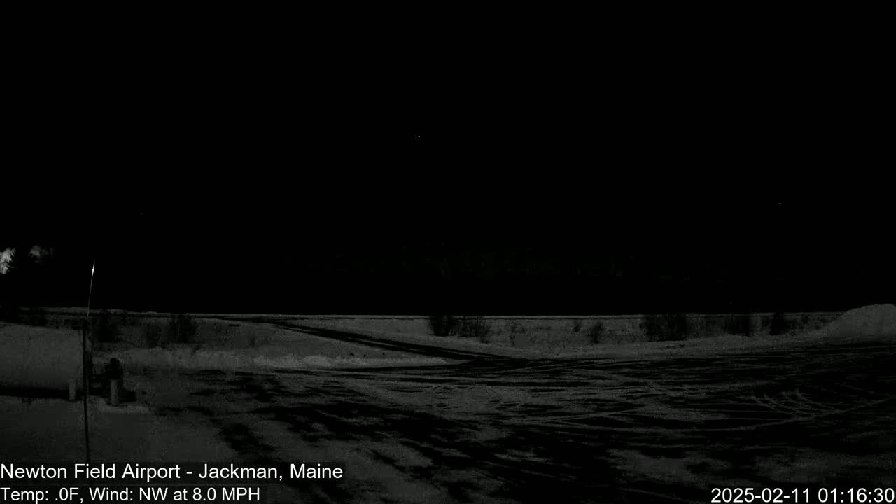 A nighttime view of a snow-covered airfield under a clear, dark sky with a northwest wind.