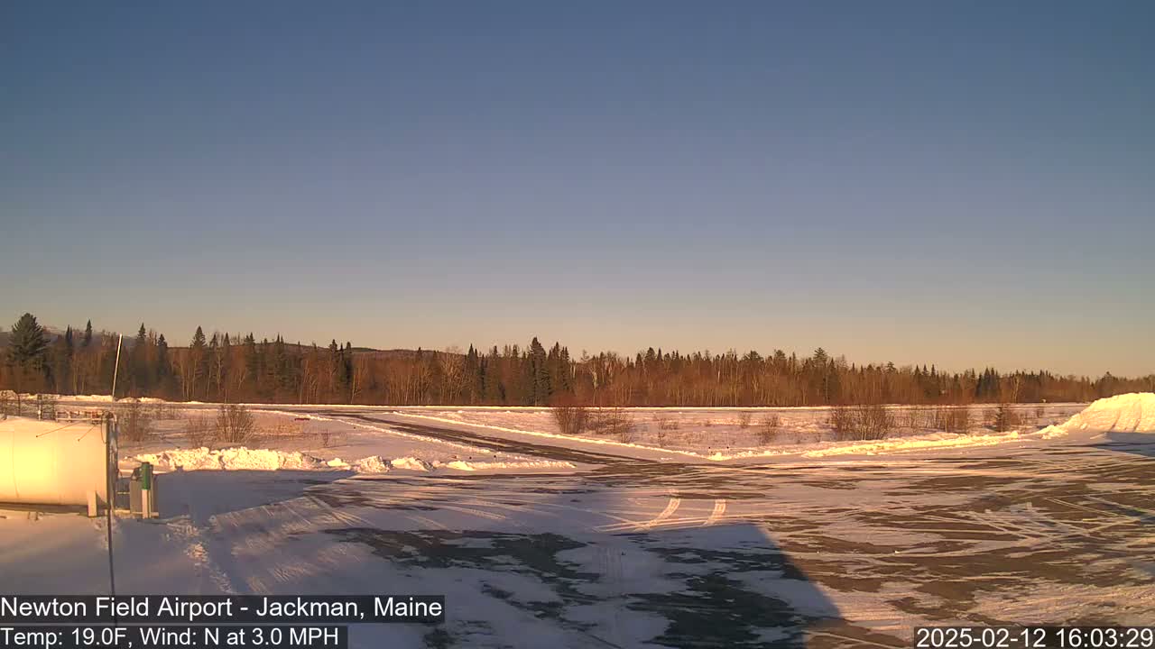 A snow-covered airfield is visible under a clear, twilight sky.