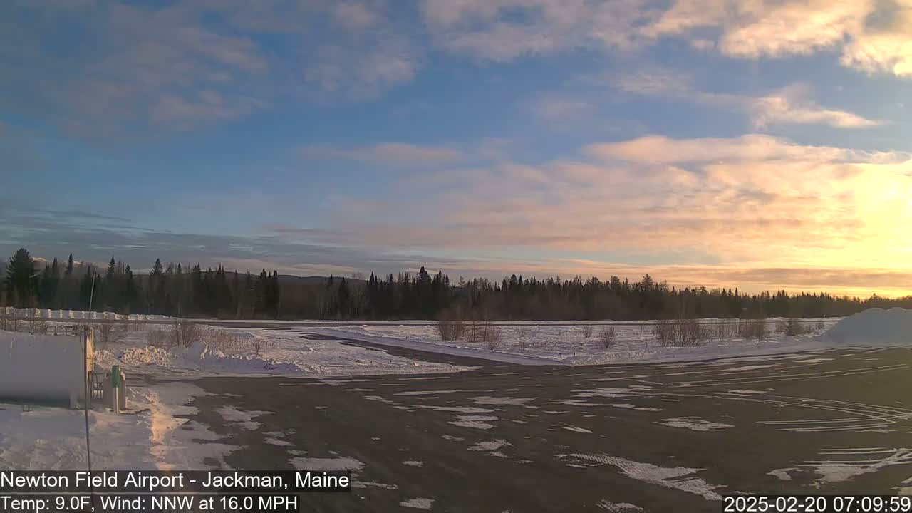 A snow-covered airfield at sunrise under a partly cloudy sky with a north-northwest wind.