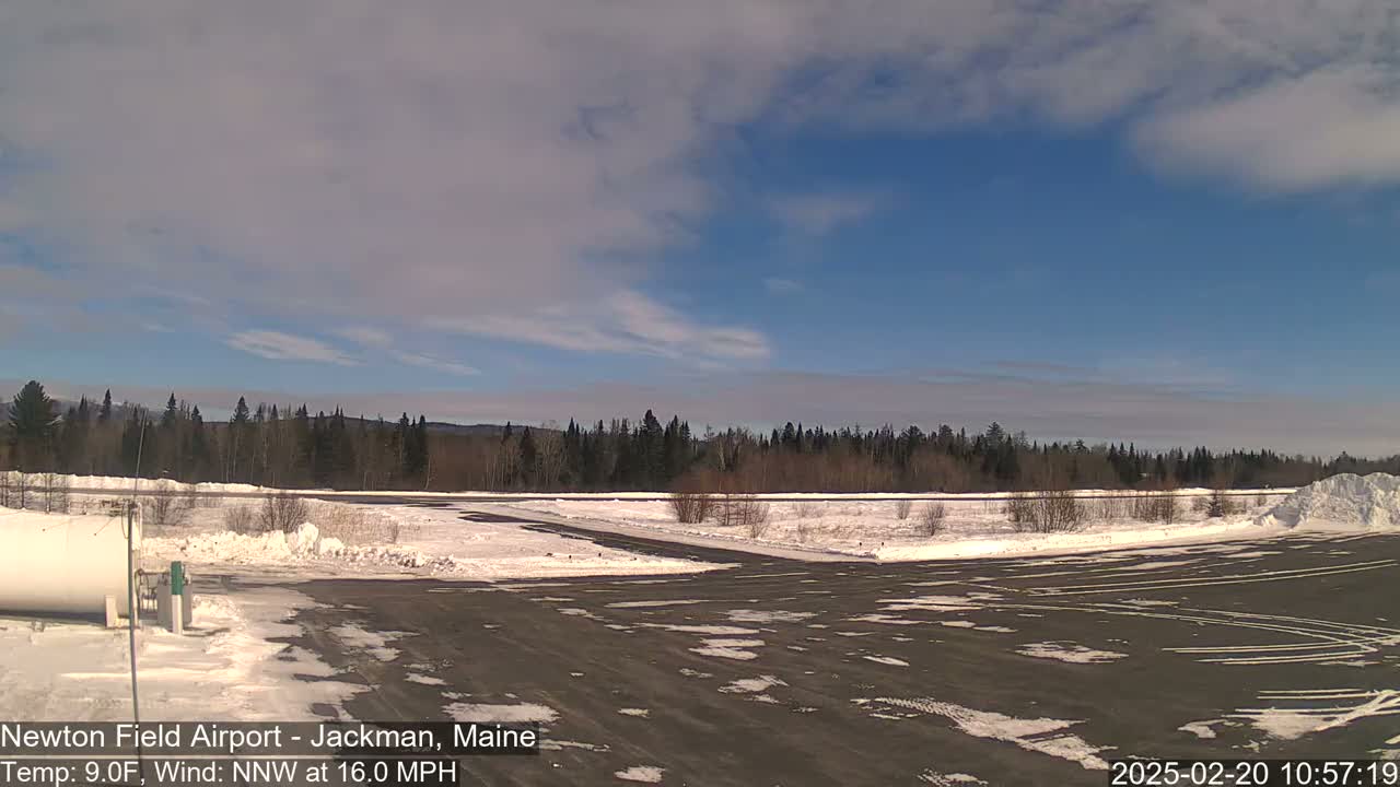 A snow-covered airfield with a partly cloudy blue sky and a northwest wind at 16 mph.