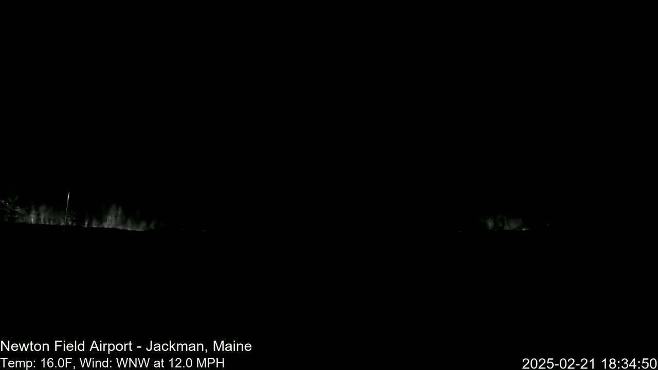 A nighttime, outdoor scene shows a dark landscape with faint, blurry light sources along the horizon under a WNW wind of 12 mph and a temperature of 16°F.