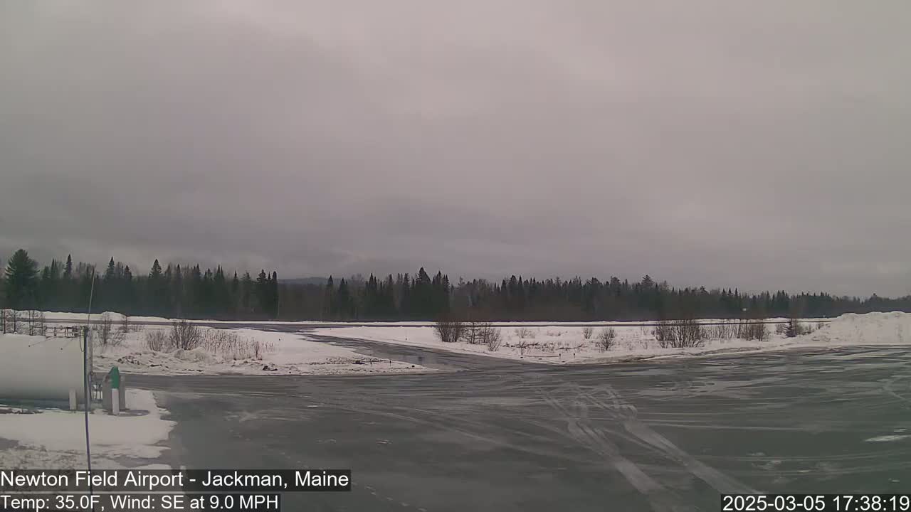 A snow-covered airport tarmac and surrounding landscape under an overcast sky.