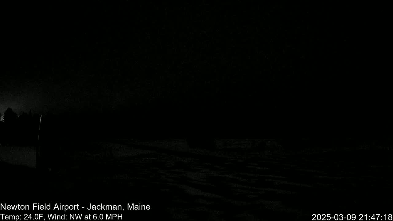 A dark, nighttime scene shows a flat, snow-covered expanse under a clear, black sky with a northwest wind at 6.0 mph and a temperature of 24 degrees Fahrenheit.