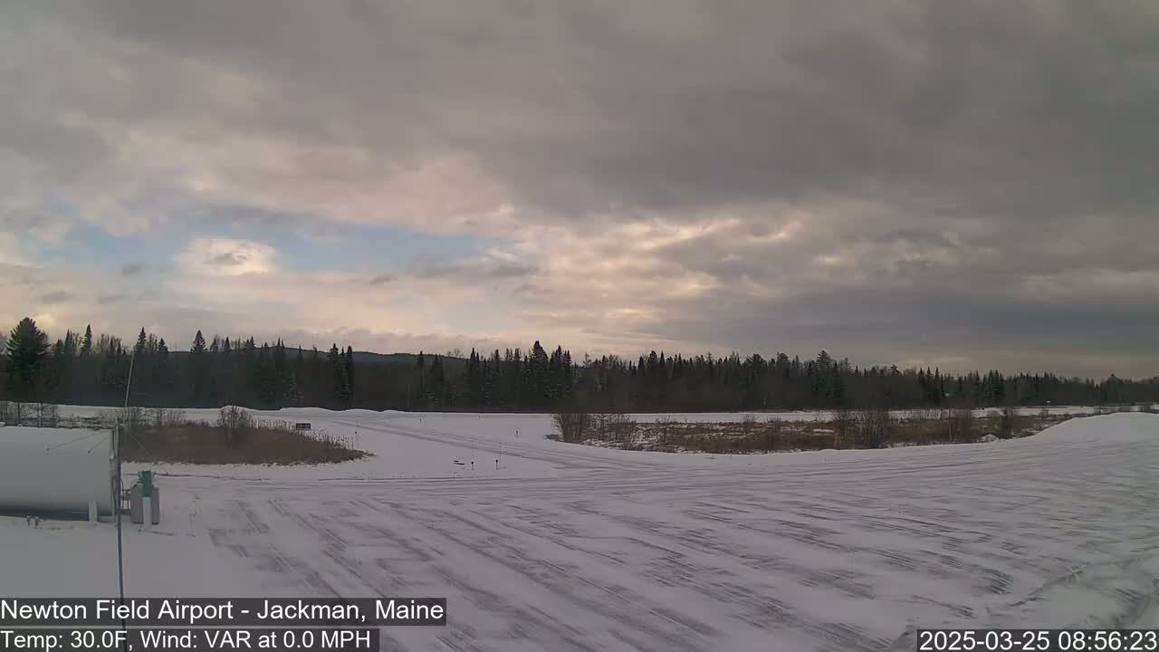 A snow-covered airfield is seen under a cloudy sky.