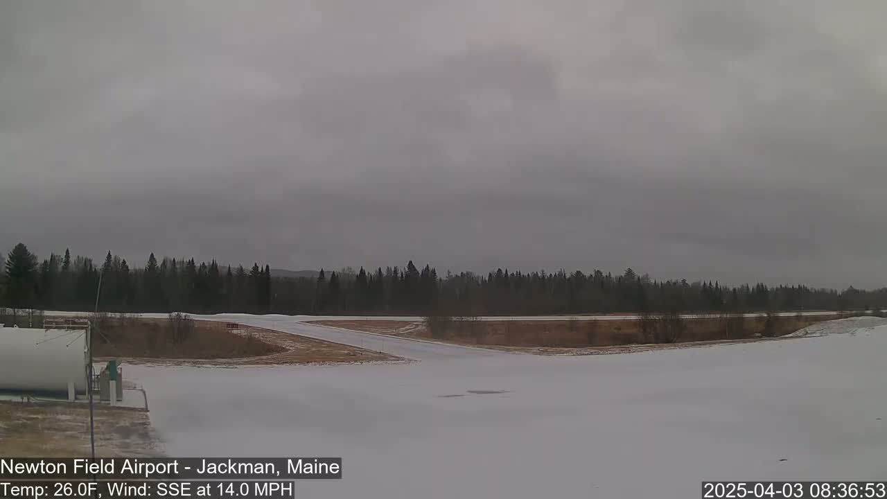 A snow-covered airfield with a dark, overcast sky and a 14 mph wind from the south-southeast.