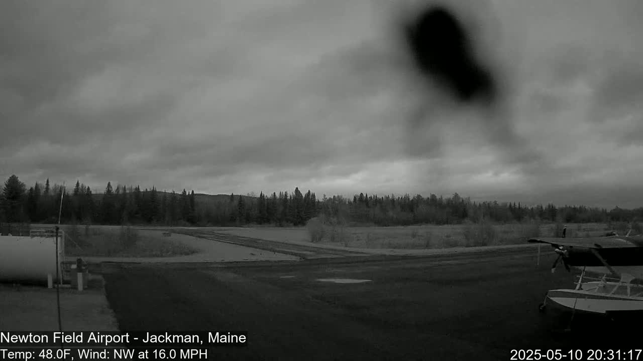 A small airplane is parked on an airfield under an overcast sky with a northwest wind of 16 mph.