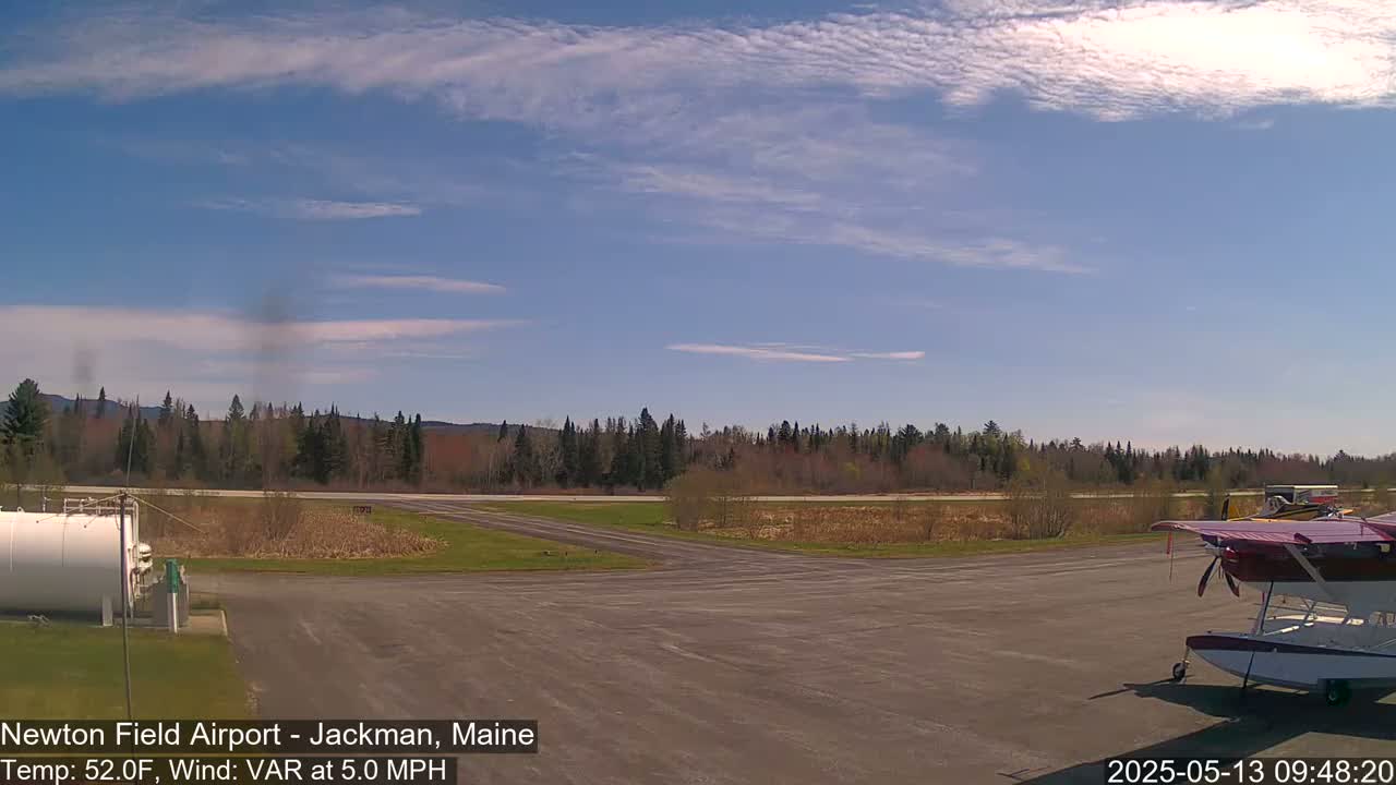 A small airport with a seaplane parked on the tarmac under a mostly clear, blue sky.