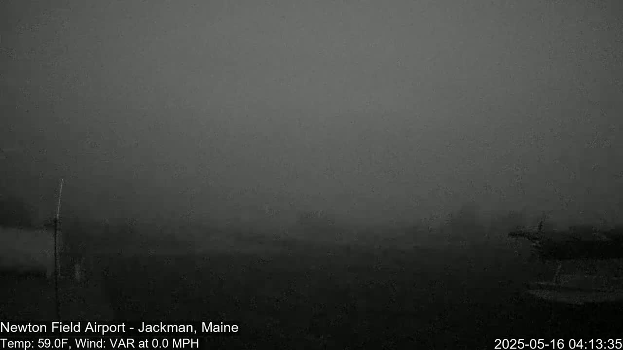 A foggy, dark gray landscape is visible with a few indistinct shapes in the mid-ground and a dark structure in the foreground.