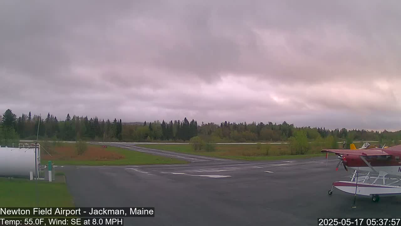 A small airfield with a seaplane parked on the tarmac under an overcast sky.