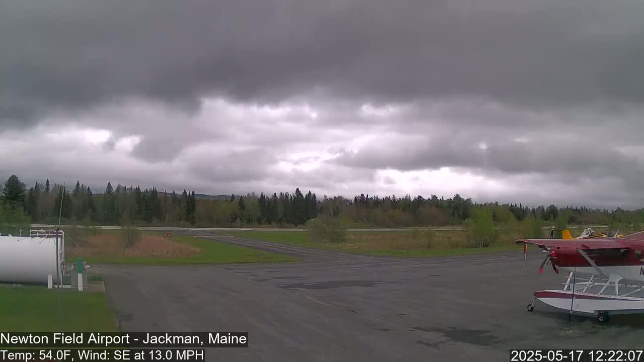 A small airport with a seaplane parked on the tarmac under an overcast sky.