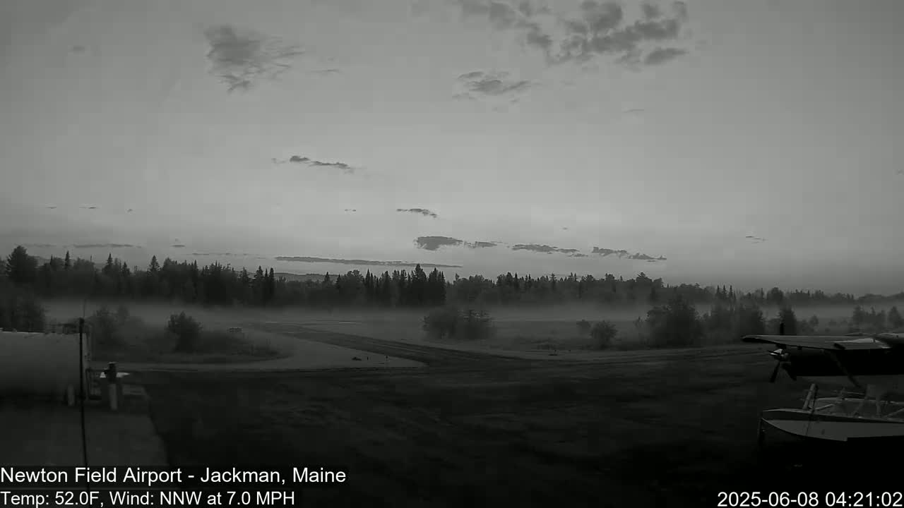 A foggy airfield at dawn is partially obscured by low-lying fog, with a seaplane partially visible in the foreground.