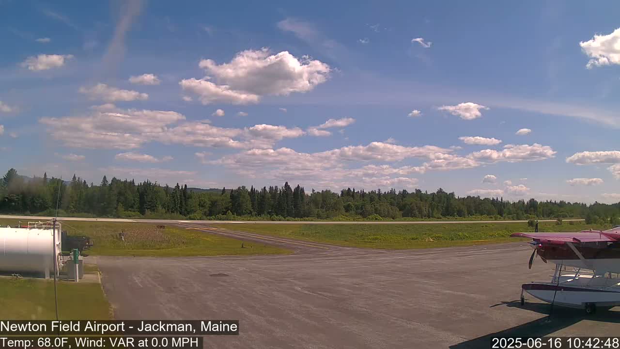 A small airport with a seaplane parked on the tarmac under a partly cloudy sky.