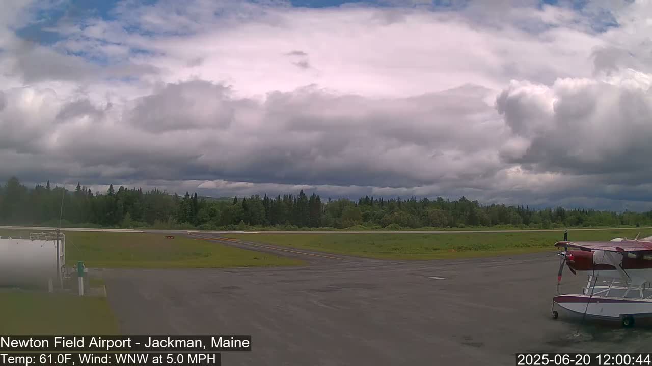 A small airfield with a seaplane parked on the tarmac under a partly cloudy sky.