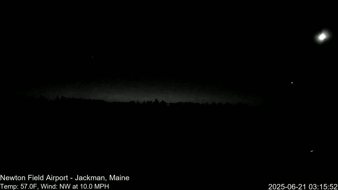 A nighttime, low-light view of a dark landscape under a mostly clear sky with a bright moon and several stars visible, a 10 mph northwest wind, and a temperature of 57°F.
