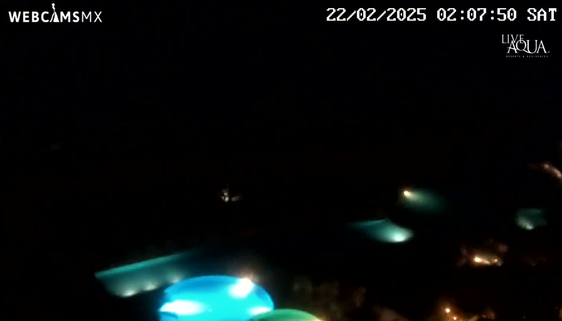 At night, several illuminated swimming pools are visible from an elevated vantage point.