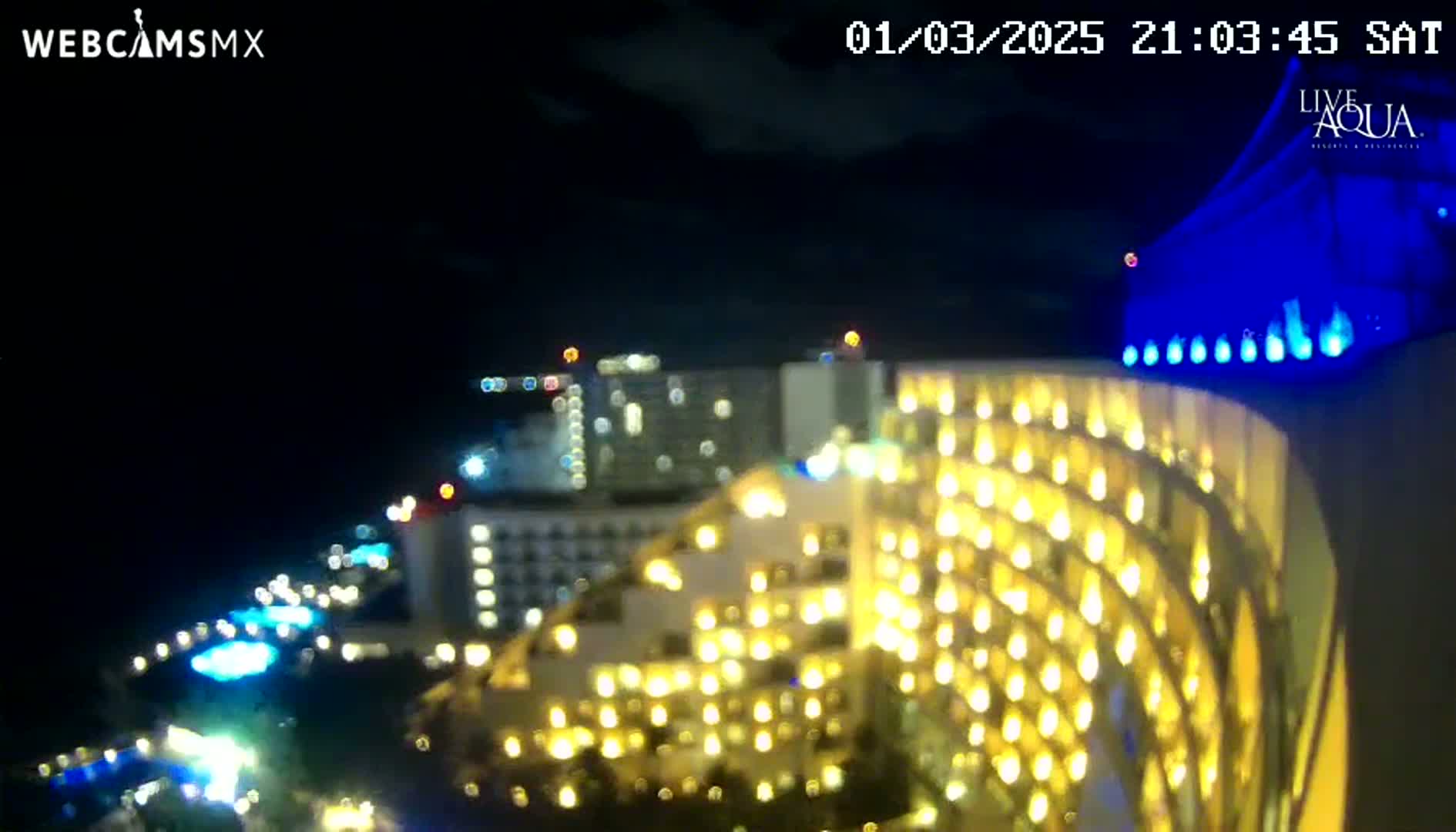 A brightly lit, multi-story hotel at night under a dark, clear sky.