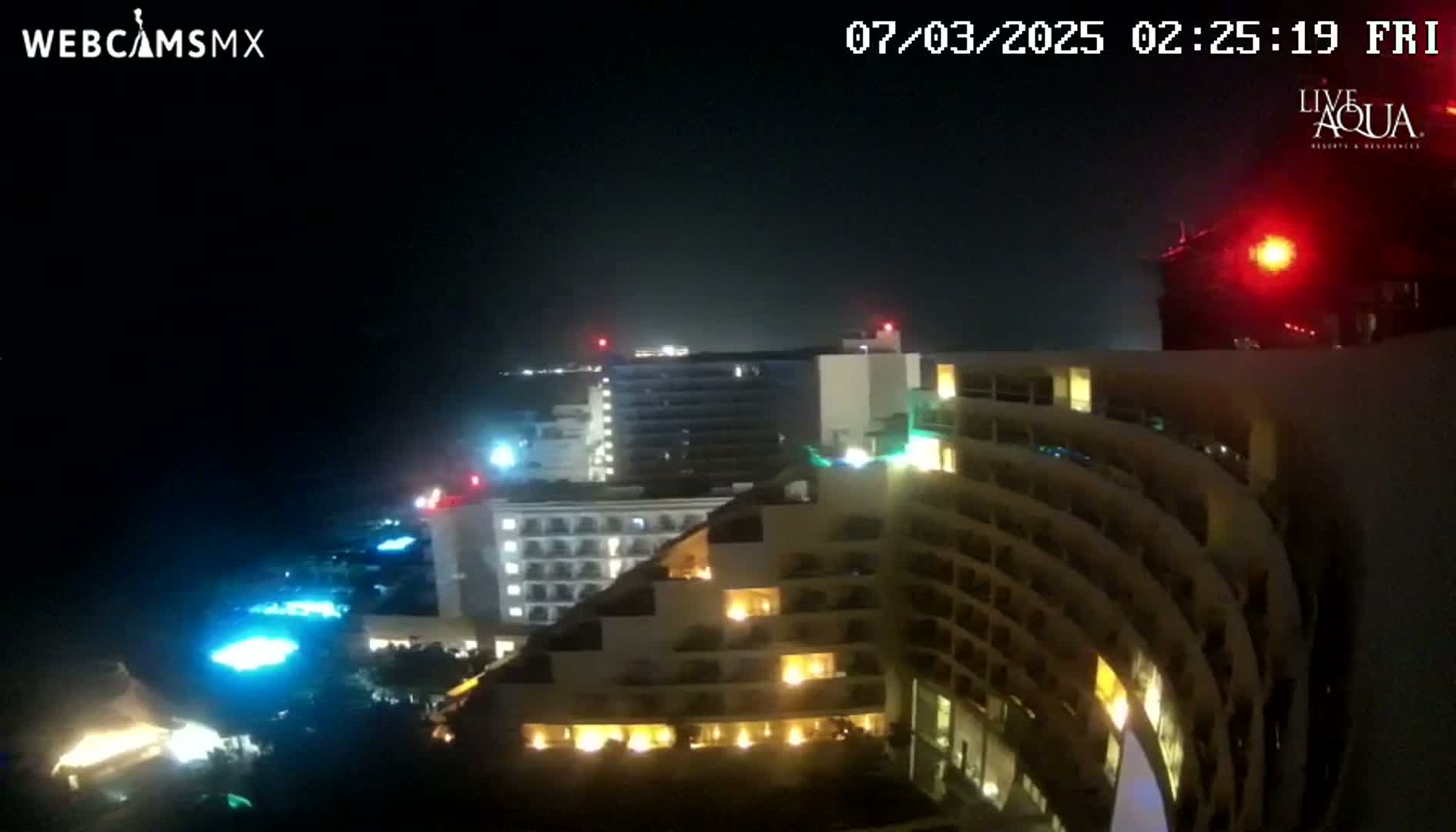 A nighttime view of illuminated high-rise hotels and resort buildings under a dark, hazy sky.