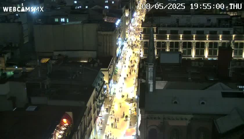 A nighttime, aerial view of a bustling city street illuminated by streetlights and building lights.
