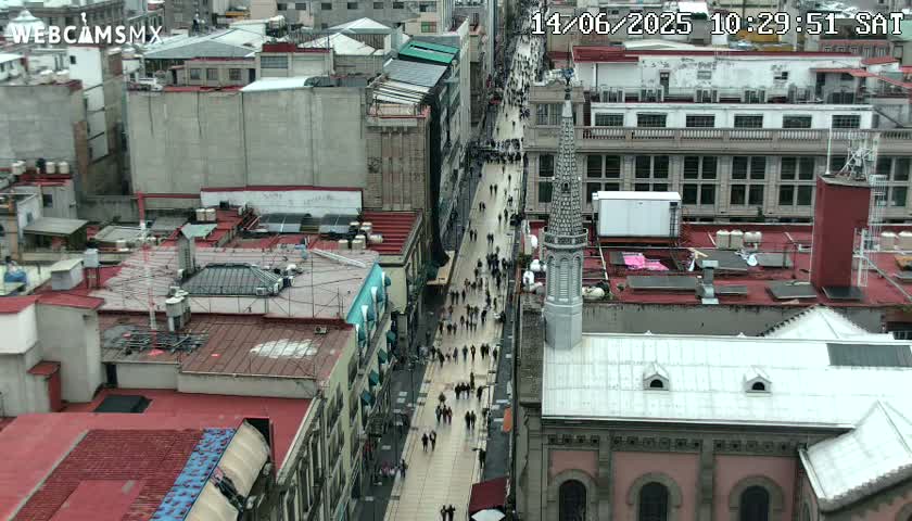 A high-angle view shows a city street crowded with pedestrians on an overcast day.