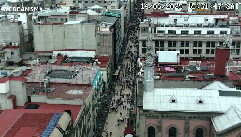 A high-angle view shows a city street crowded with pedestrians on an overcast day.