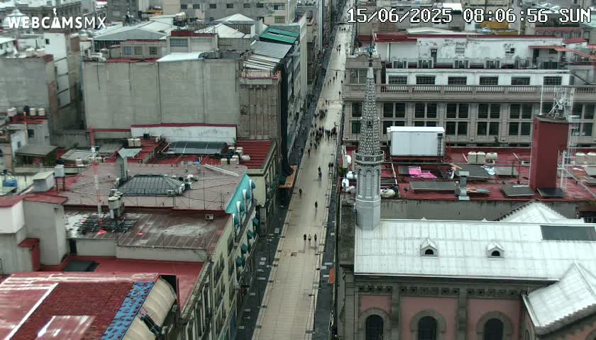 An aerial view of a city street with many people walking, under overcast skies.