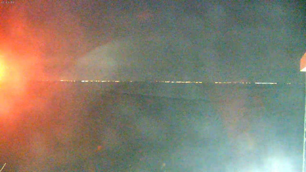 A distant line of lights is visible on a dark, nighttime horizon.