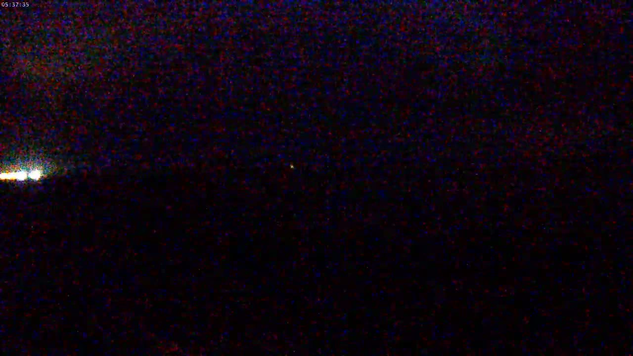 A nighttime image shows a dark sky with two faint lights appearing on the horizon.