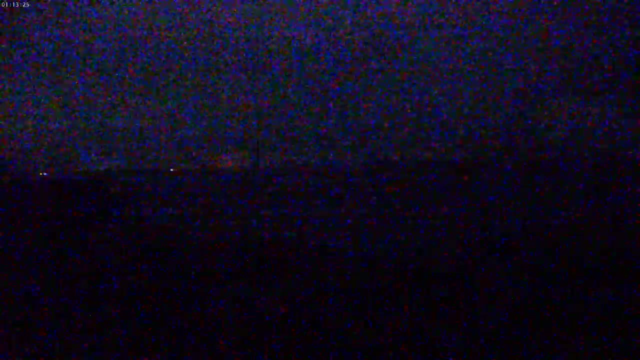 A dark, nighttime landscape is visible, with a few faint lights in the distance.