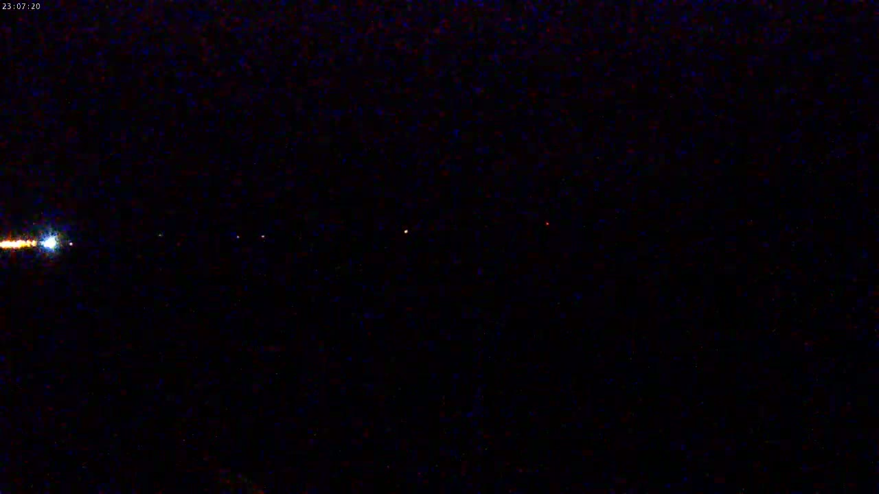 A nighttime image shows several faint lights horizontally aligned across a dark sky.