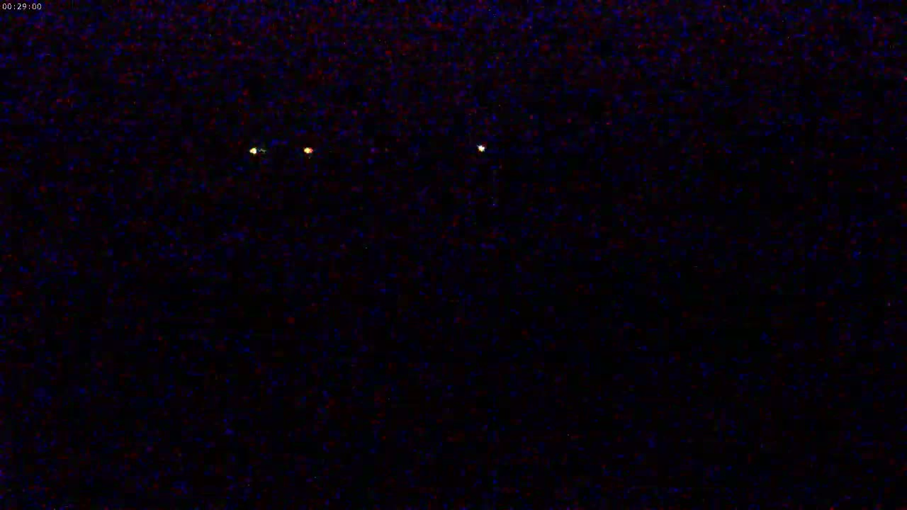 At night, three faint lights are visible in the distance across a dark, textured background.