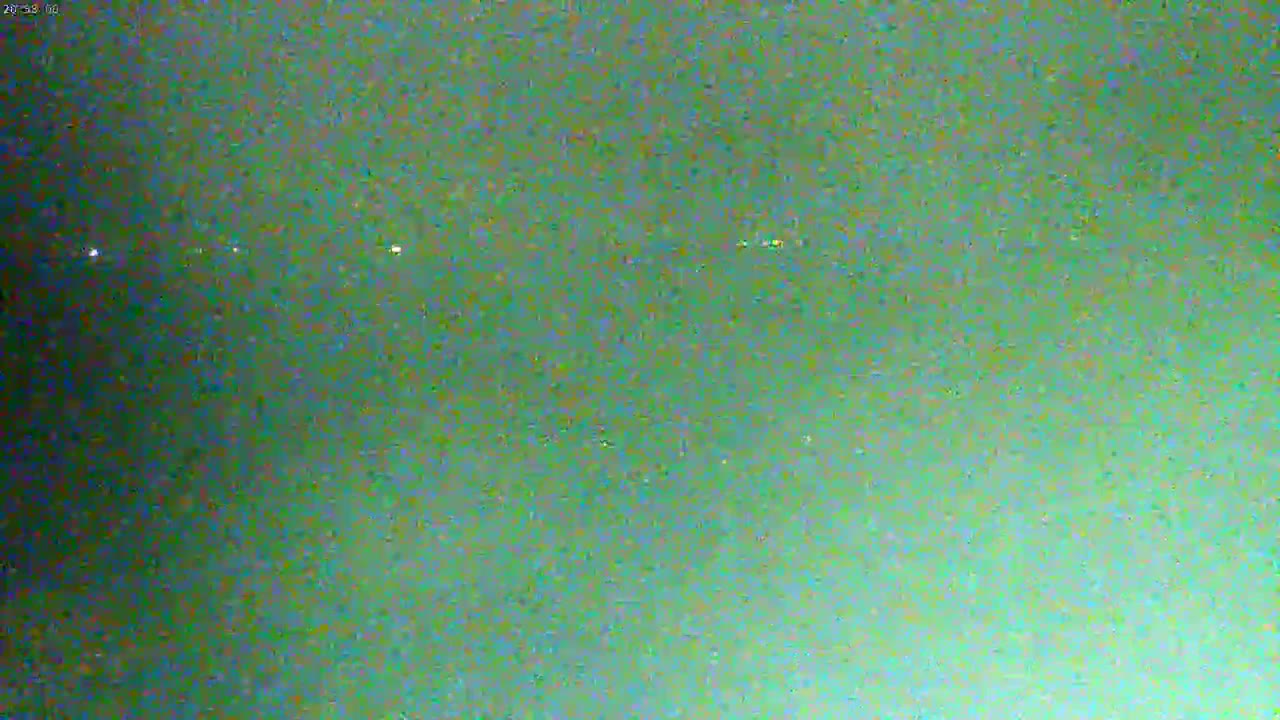 A blurry, dark green image shows several faint, distant lights at night.
