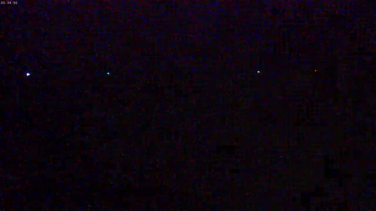 A dark nighttime scene shows several small, faint lights in the distance.