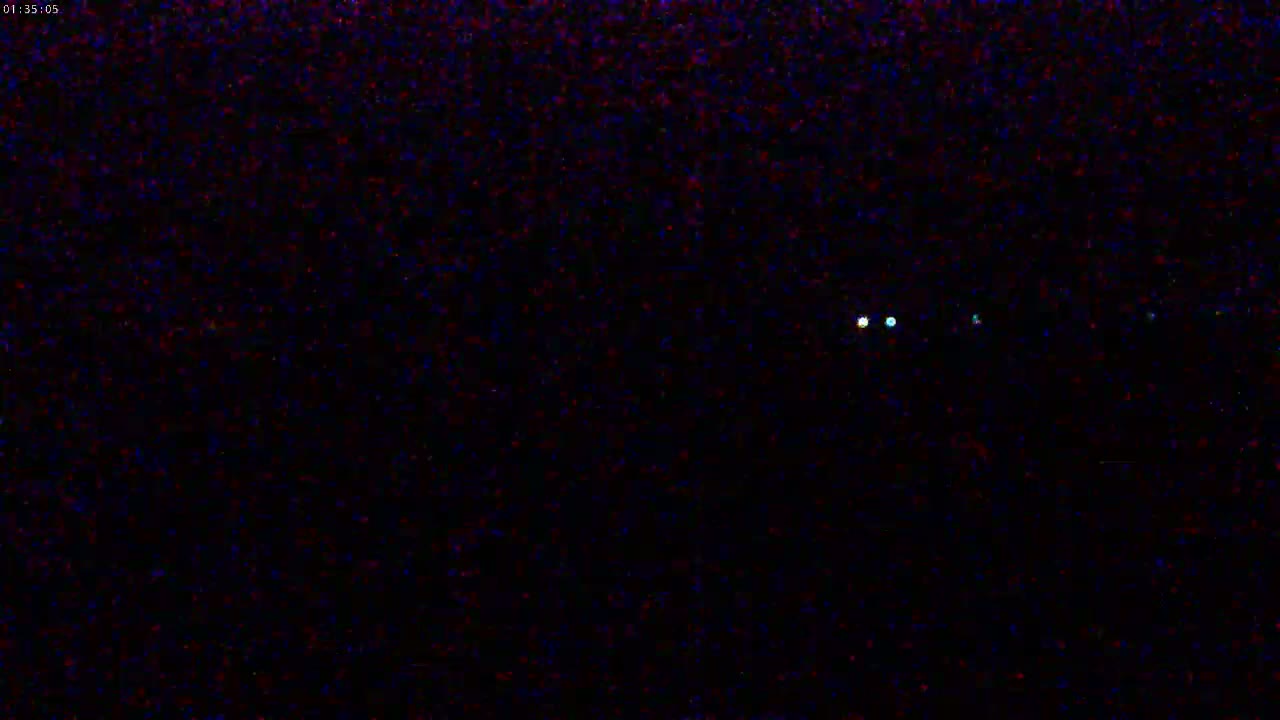 A dark, nighttime scene shows several small, bright lights in the distance.