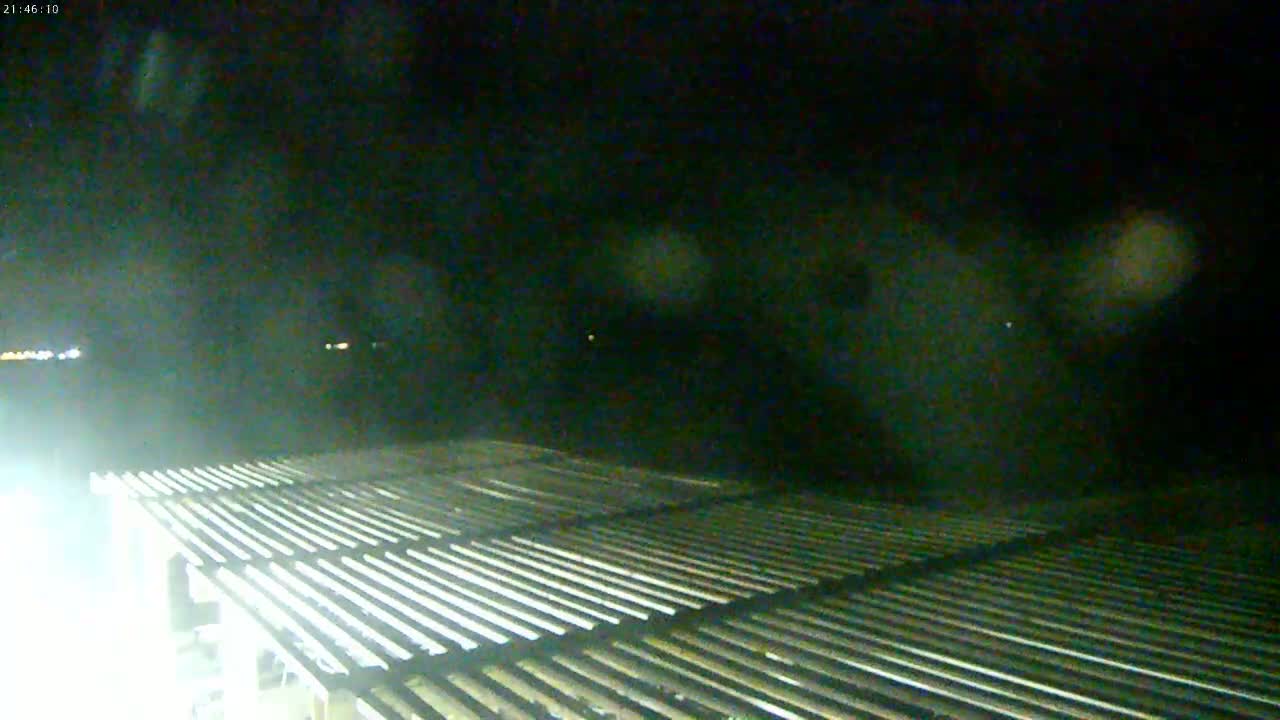 A nighttime, dimly lit view shows a slatted surface extending from the foreground into the middle ground, with a dark, possibly cloudy sky above.