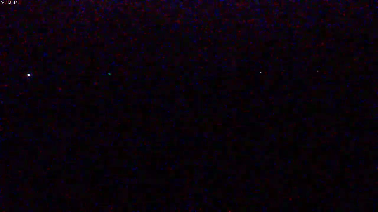 A nighttime image shows a dark sky with a few faint lights visible.