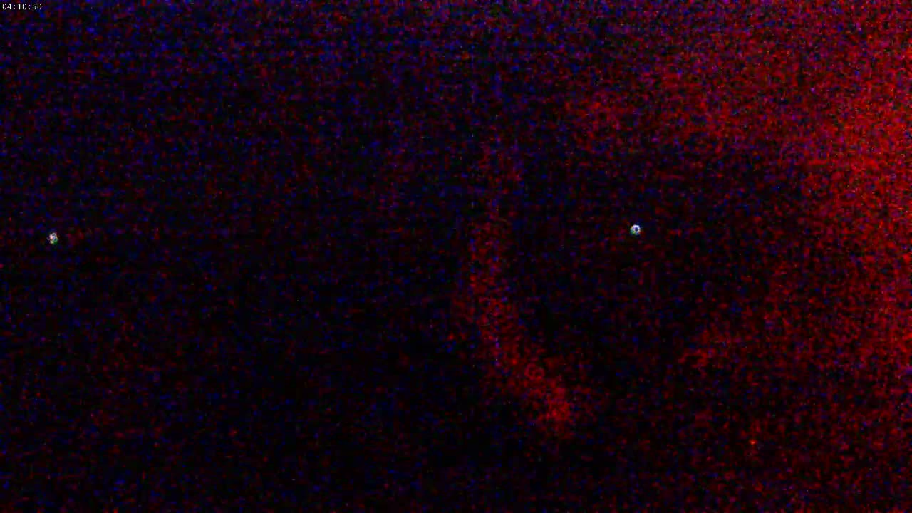 A nighttime image shows a dark, textured surface with two small, bright lights.