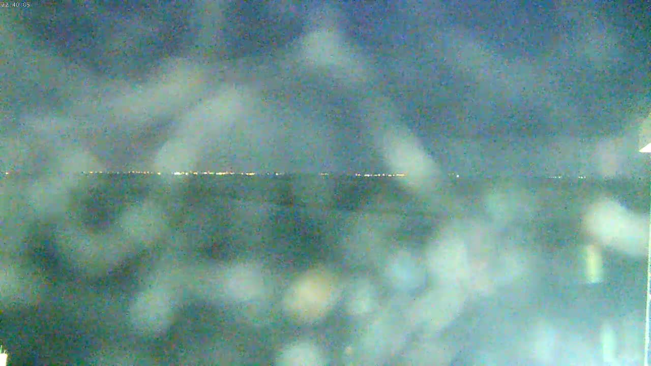 A nighttime view shows a distant line of lights across a hazy, blurry landscape.