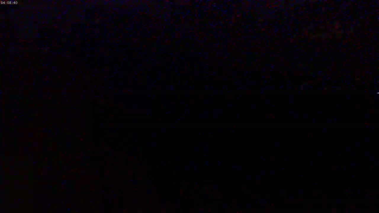 A dark, grainy image shows a mostly black scene with some faint, speckled light.