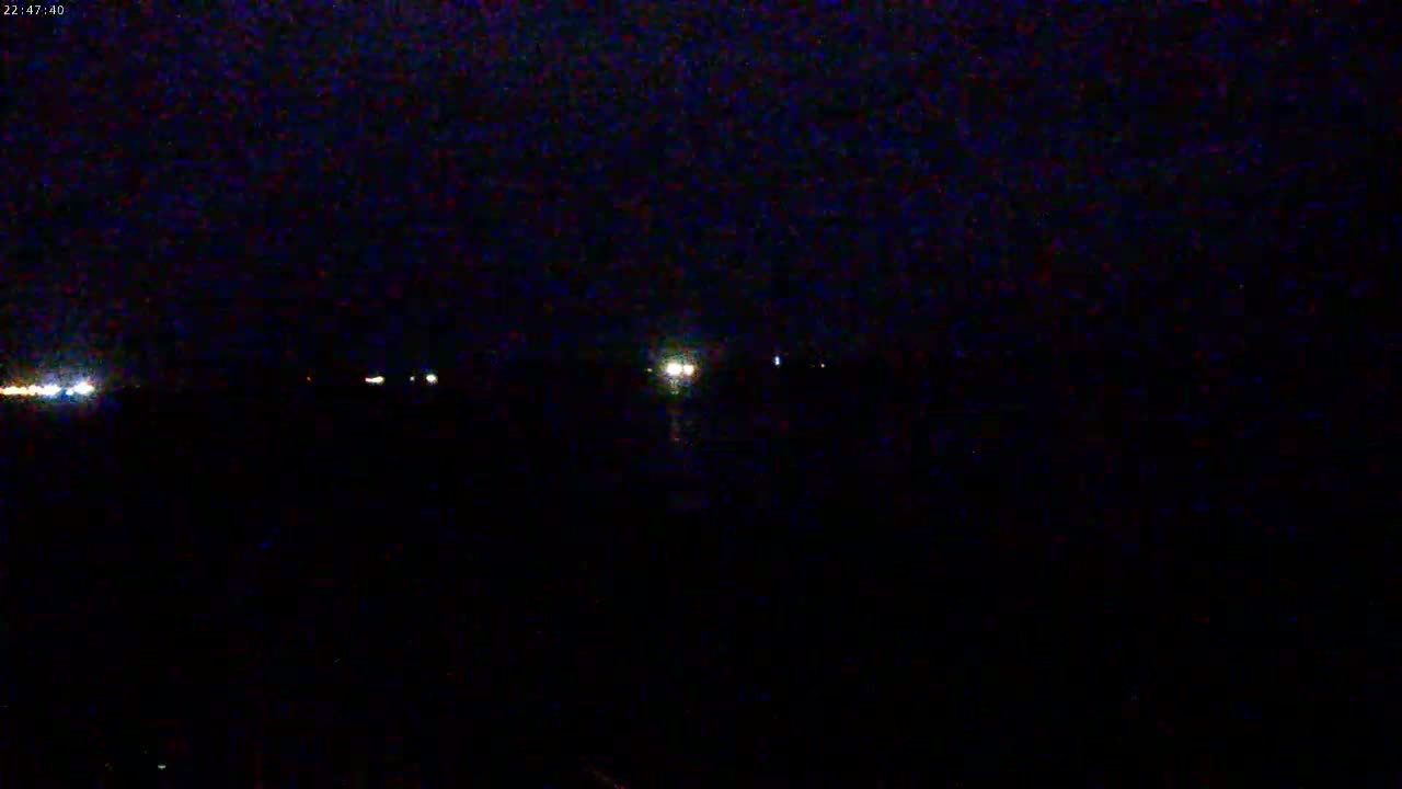 A dark, nighttime scene shows a few distant lights on the horizon.