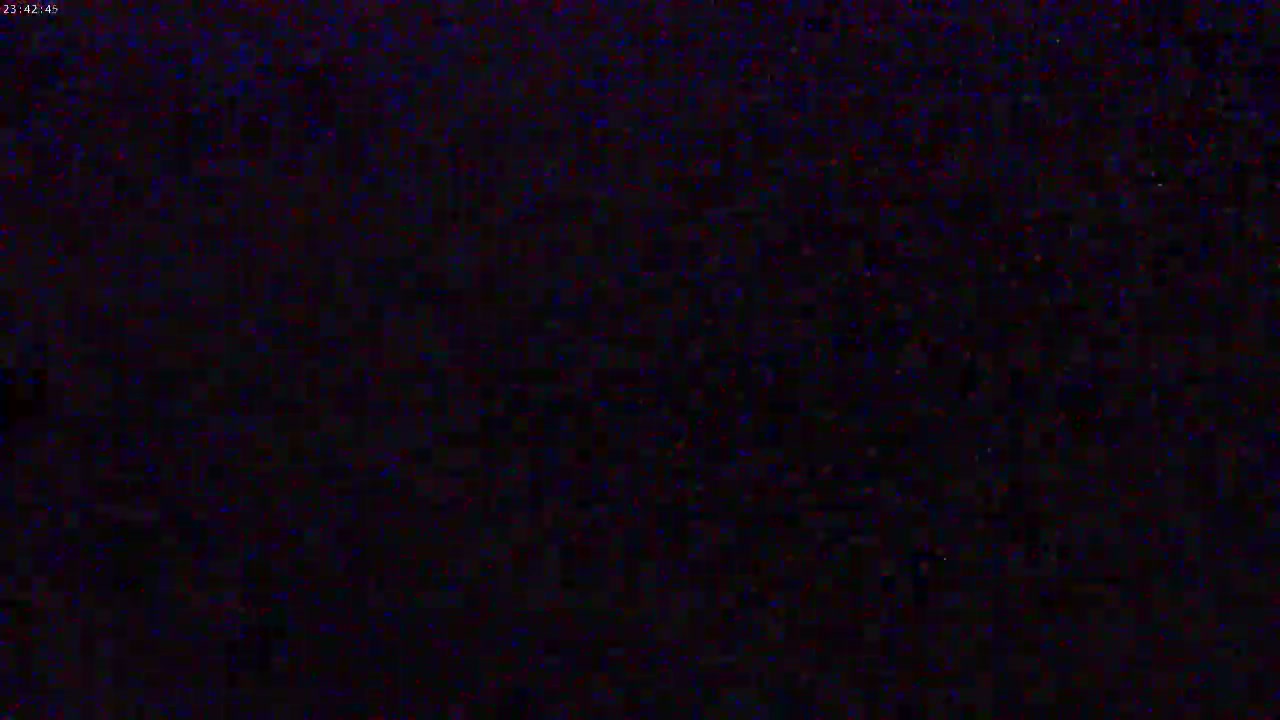 A dark, grainy image with indistinct details shows a mostly black field with slight variations in shades of dark blue and red.