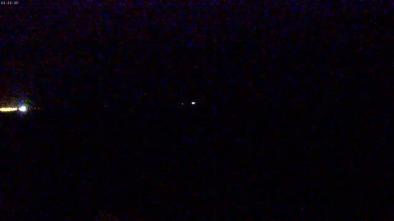 A nighttime image shows two bright lights, one appearing as a streak, in a dark sky.