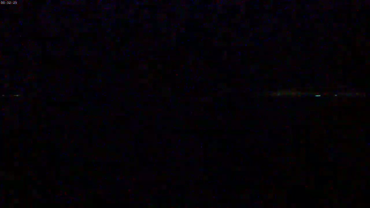A very low-light image shows a faint horizontal line of light on the horizon at night.