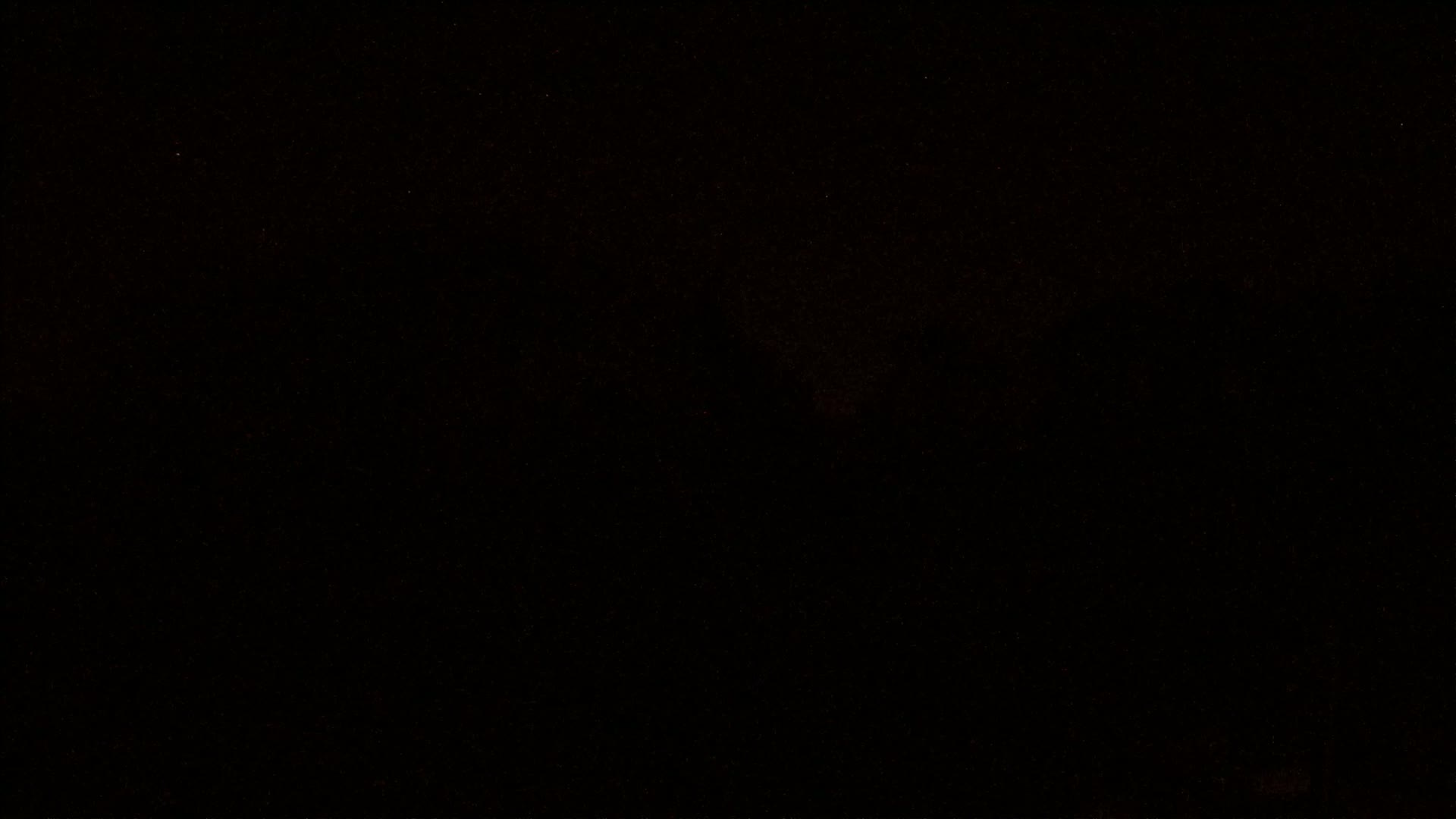 A very dark image shows a mostly black background with faint, sparse orange speckles.