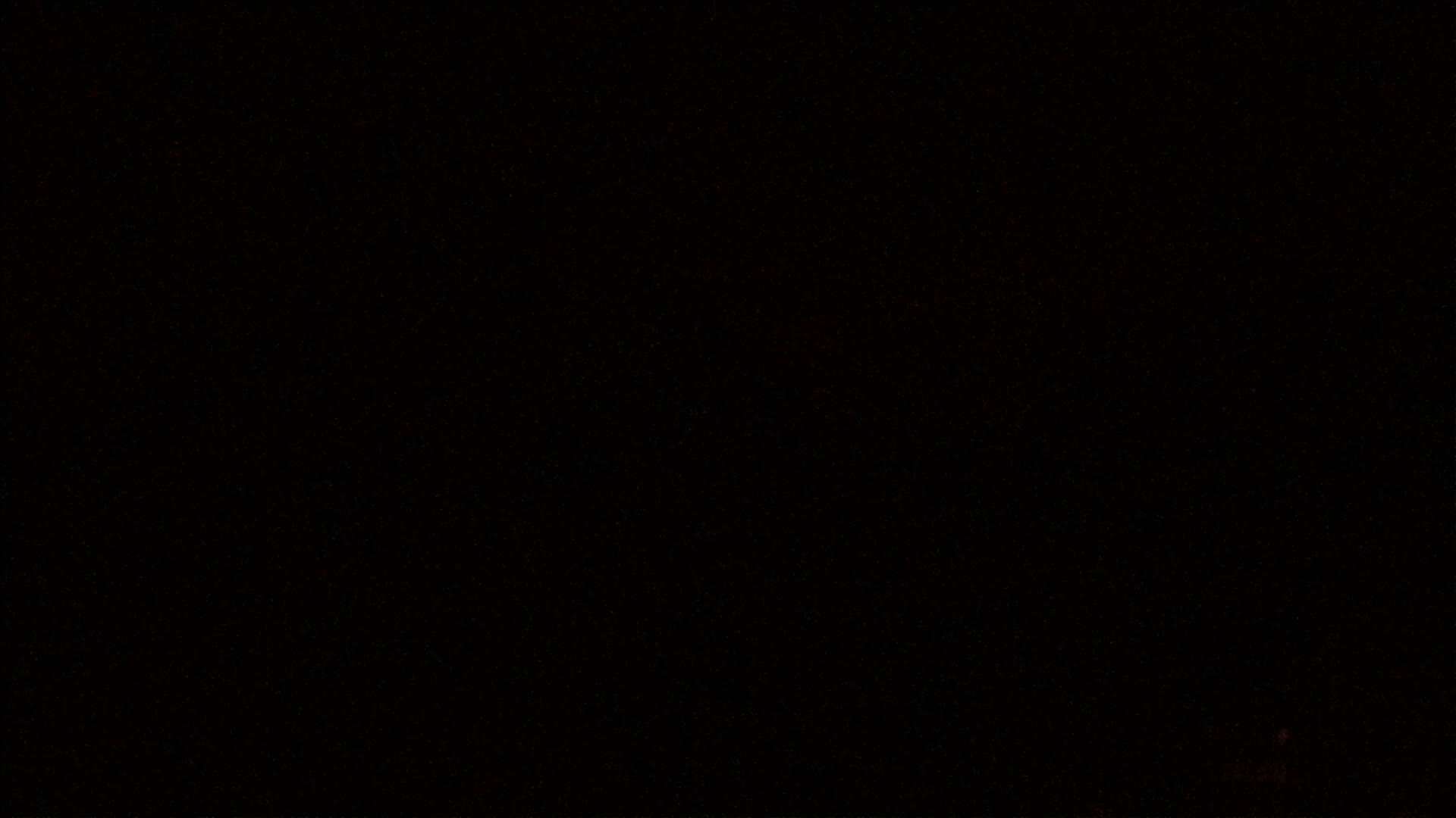 The image is a mostly black field with sparsely scattered tiny red and orange flecks.