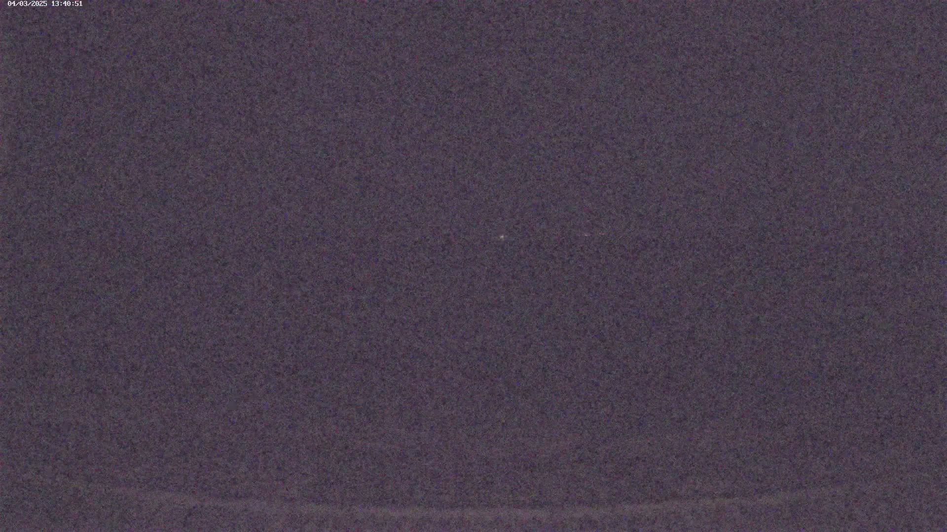 A dark purplish-gray image shows a mostly uniform texture with a few faint lighter specks.