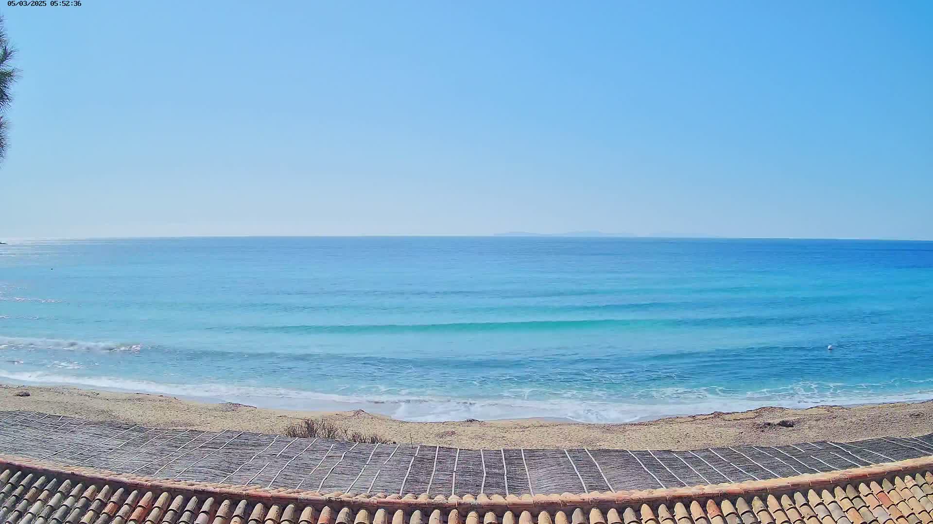 A sandy beach with gentle waves on a clear, sunny day.