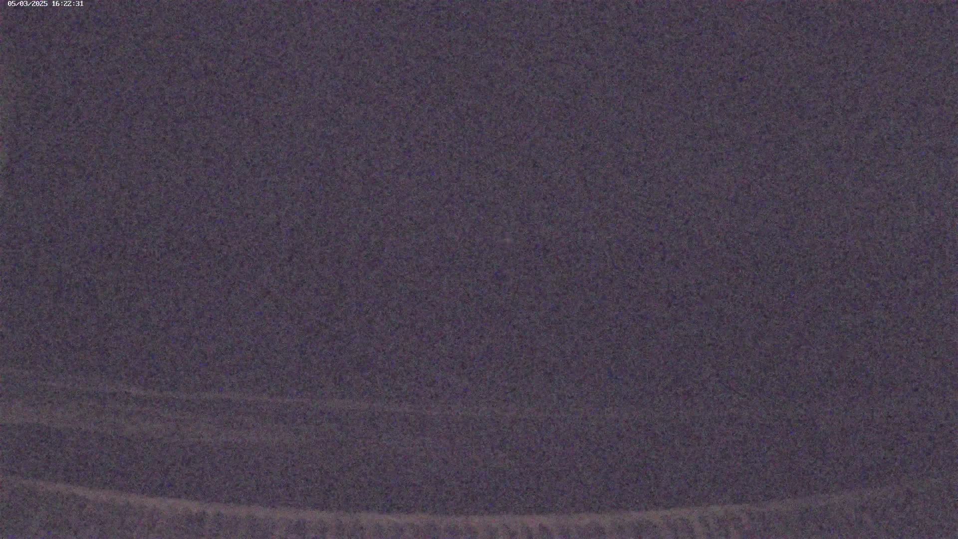 A dark purplish-gray, grainy image shows a mostly featureless sky at night.